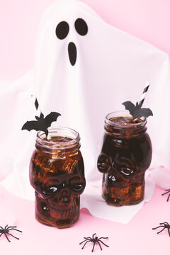 Spooky skull drinks with bats and ghost on pink background, Halloween party treats