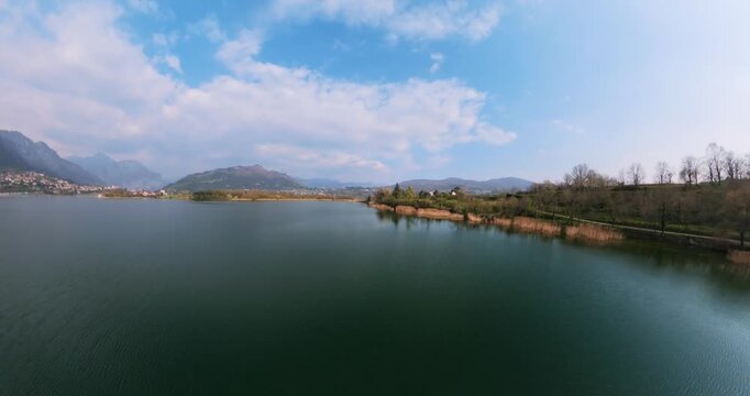 Captivating aerial 360 pull-back shot revealing Lake Annone's tranquil waters and Monte Barro's majestic presence.