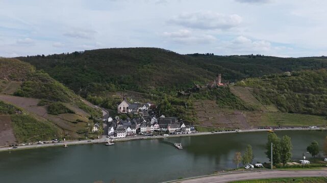 Stunning aerial push forward over the picturesque Cochem town, revealing its charming architecture nestled by the tranquil Moselle River and majestic castle.