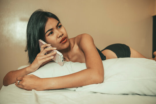 Adult woman in lingerie argues with her boyfriend by phone while lying in bed, showing relationship conflict, or possibly late for an intimate moment frustrating her.