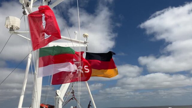 Colorful ferry flags waving above passenger deck during sea crossing near Helgoland viewed from onboard perspective