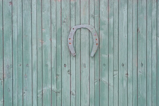 Ferro di cavallo portafortuna appeso a una vecchia parete di legno verde
