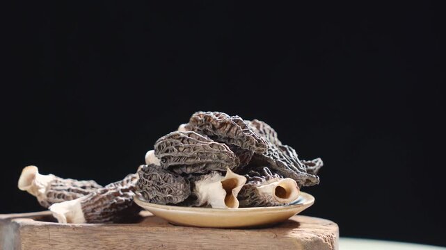 Morel Mushrooms Rotating on Wooden Surface in Dark Mood