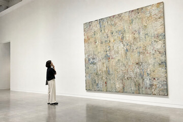 Fototapeta premium 展示室で大きな絵画を見る女性