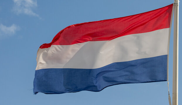 Dutch national flag waving in wind against clear blue sky background