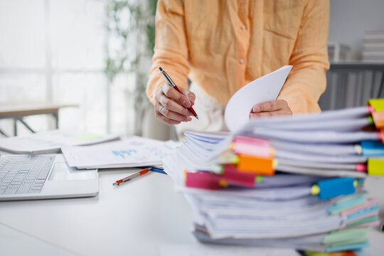 Businesswoman hands working in Stacks of paper files for searching and checking unfinished document achieves on folders papers at busy work desk office