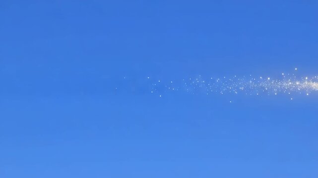 Fiery projectile blazing across a clear blue sky leaving a sparkling trail during daylight