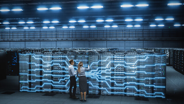 IT Specialist and Engineer Stand in data center, work, Activating Network Overlay Across Server Racks. Verify Connections, Monitor System During Cloud Infrastructure Cybersecurity Operations