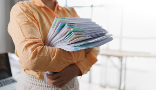 Business woman Auditor Holding Large Stack of Financial Documents working with financial documents Files in the office