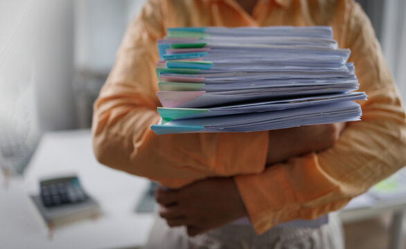Business woman Auditor Holding Large Stack of Financial Documents working with financial documents Files in the office