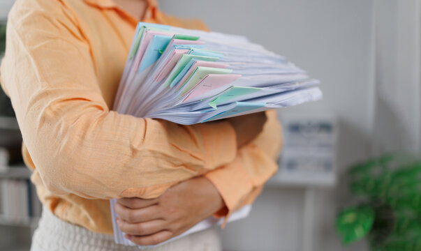 Business woman Auditor Holding Large Stack of Financial Documents working with financial documents Files in the office