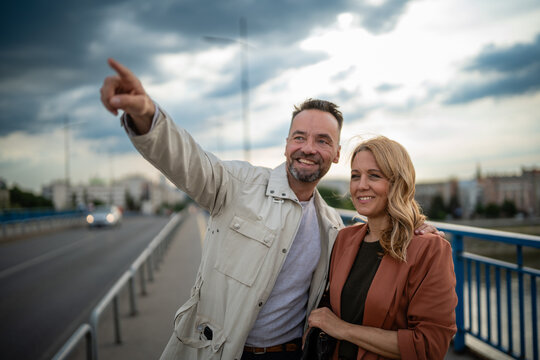 Smiling couple exploring city, man pointing forward