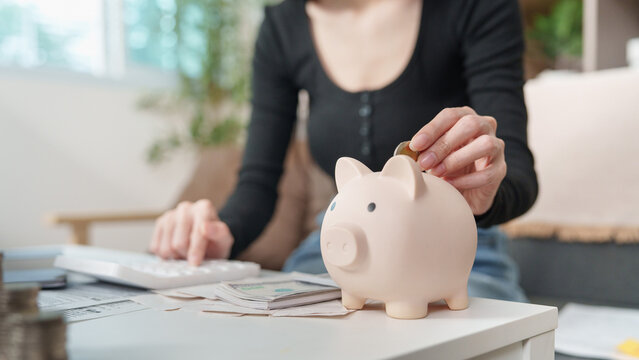 Woman putting coin into piggy bank for financial savings and tax planning