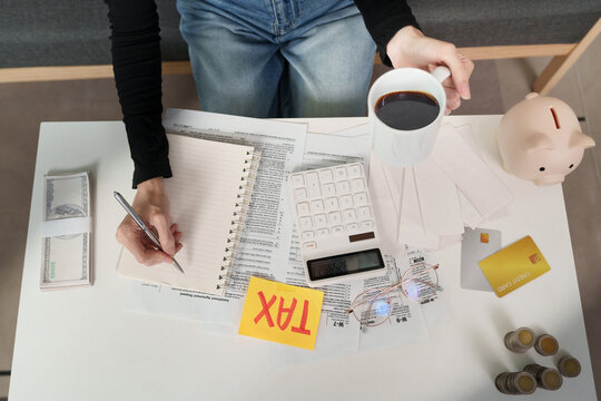 Top view of woman calculating tax payment with documents and money on desk