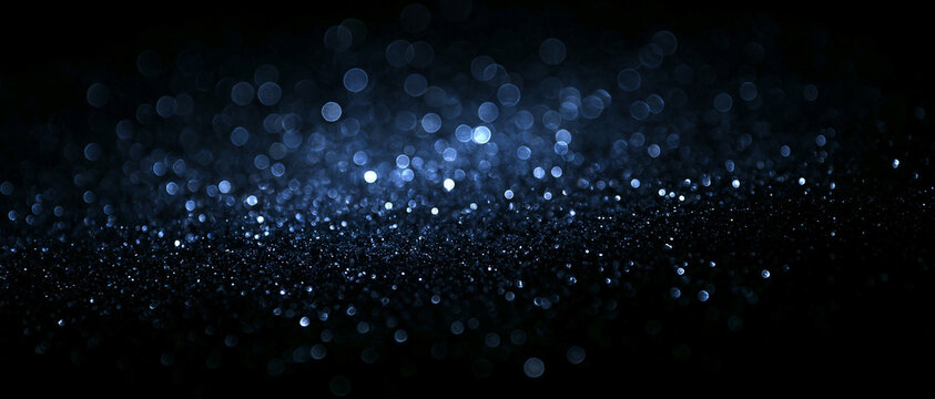Abstract blue glitter bokeh light effect on dark background. Glowing shimmering particles, focus circular lens flare texture. Futuristic glowing luxury backdrop banner, celebration, digital overlays.