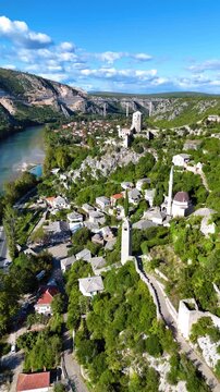 Aerial view of the historic village of Pocitelj with its stone houses, minaret, and clock tower nestled along the Neretva river in Pocitelj, Federation of Bosnia, Bosnia and Herzegovina.