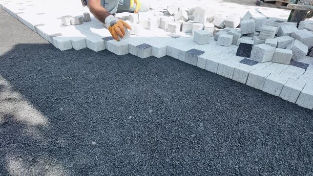 Construction Worker Laying Concrete Paving Stones on Street Sidewalk, Male Paver Installing Interlocking Cobblestone Bricks for Pathway Construction Site, Close Up High Angle View