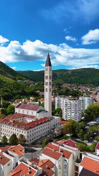 Aerial view of the Franciscan Church of St. Peter and Paul Bell Tower rising above the red-tiled rooftops of the city in Mostar, Federation of Bosnia, Bosnia and Herzegovina.