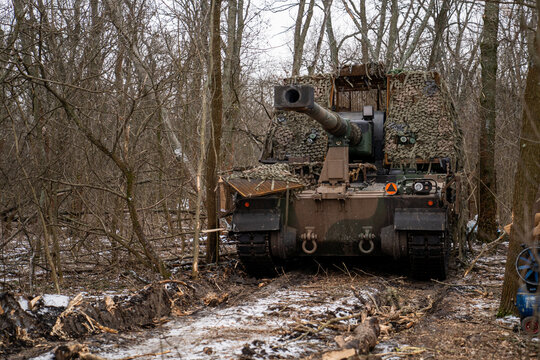 AHS Krab self-propelled howitzer of the Ukrainian Armed Forces camouflaged with a camouflage net and positioned in a winter forest. 