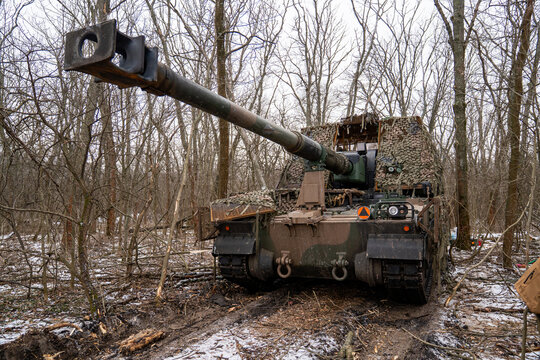AHS Krab self-propelled howitzer of the Ukrainian Armed Forces camouflaged with a camouflage net and positioned in a winter forest. 
