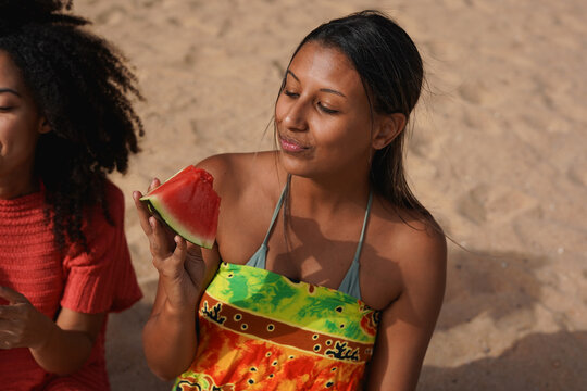 Happy latin woman eating watermelon on the beach during summer vacation - Holiday, multiracial girls and food concept