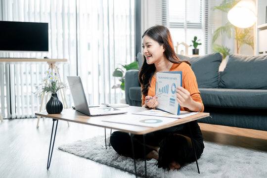 Young asian woman working from home, smiling and presenting business data during a video conference call, collaborating remotely using technology for online meetings