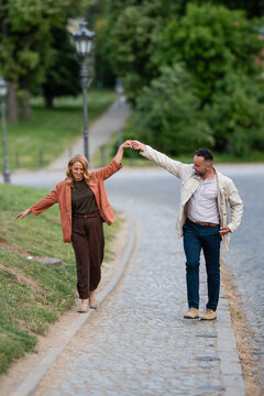 Happy couple holding hands walking city park path