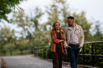 Naklejka premium Couple walking arm in arm, enjoying park conversation