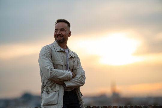 Smiling man standing confidently during sunset golden hour