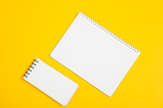 Open blank checked notepad and pen, yellow background. Mockup with copyspace.