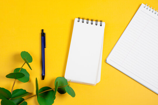 Open blank checked notepad and pen, yellow background. Mockup with copyspace.