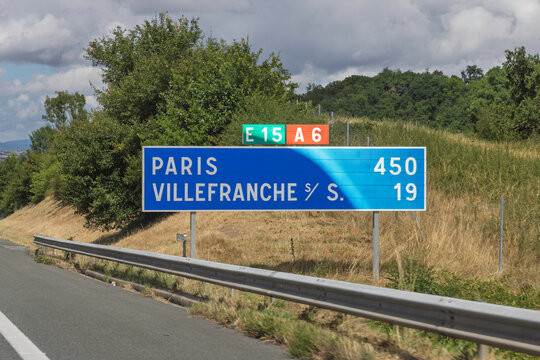 France. Blue roadside distance sign on the A6 highway indicating 450 km to Paris and 19 km to Villefranche sur Saone.