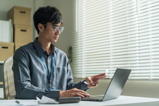 Office worker wearing glasses using laptop computer to check receipt and financial bills at desk.