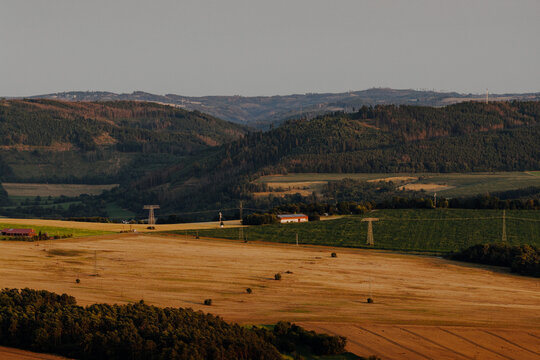 Rural landscape with harvested fields, forested hills and power lines in Germany