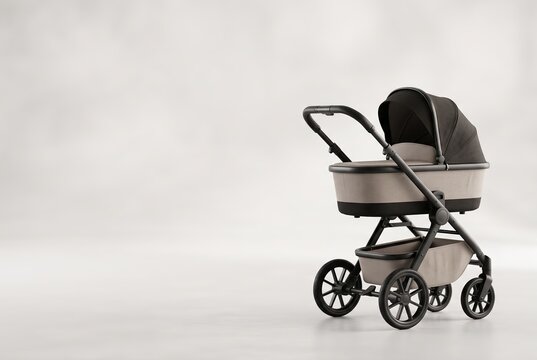 A stroller sits on a light background showing its design and wheels. The stroller has a dark canopy and a neutral color scheme. The setting has no other objects or people