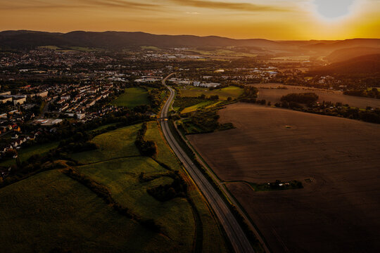 Spectacular aerial sunset landscape with a curving highway and rural town named Saalfeld