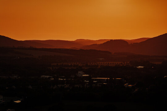 Hazy orange sunset silhouette of rolling hills and a rural town in Thuringia