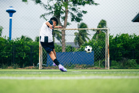 Kid boy leg kicking soccer ball on green grass field action. conceptual metaphor for youth sports training team competition fitness health wellness and active lifestyle