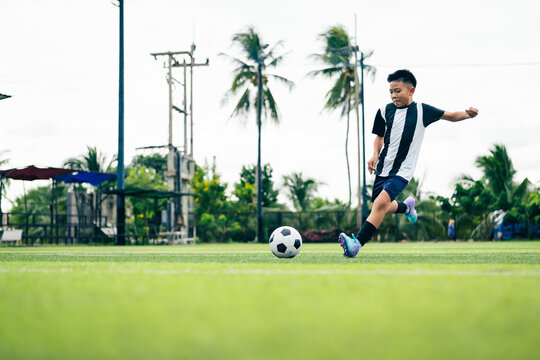 Kid boy leg kicking soccer ball on green grass field action. conceptual metaphor for youth sports training team competition fitness health wellness and active lifestyle