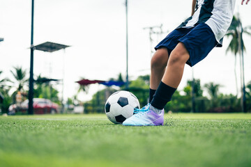 Obraz premium Kid boy leg kicking soccer ball on green grass field action. conceptual metaphor for youth sports training team competition fitness health wellness and active lifestyle