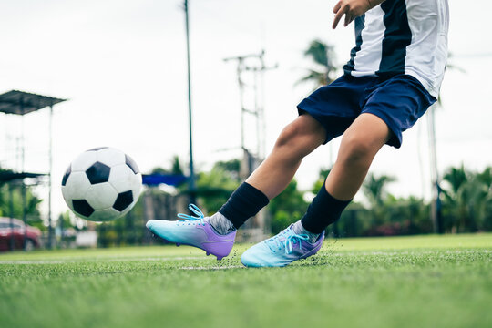 Kid boy leg kicking soccer ball on green grass field action. conceptual metaphor for youth sports training team competition fitness health wellness and active lifestyle
