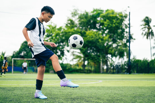 Kid boy leg kicking soccer ball on green grass field action. conceptual metaphor for youth sports training team competition fitness health wellness and active lifestyle
