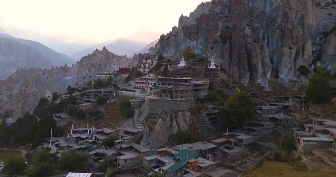 Annapurna CIrcuit, Manang Nepal, aerial slow gliding shot of traditional stone village architecture and ancient Bhraka Monastery nestled on a rugged mountain cliffside