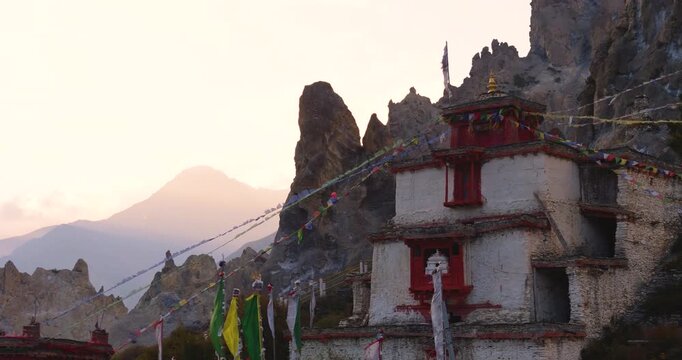 Annapurna Circuit, Manang, Nepal, drone pull-out shot starting near the red and white roof of Bhraka Monastery and expanding to reveal distant Himalayan mountain ranges.