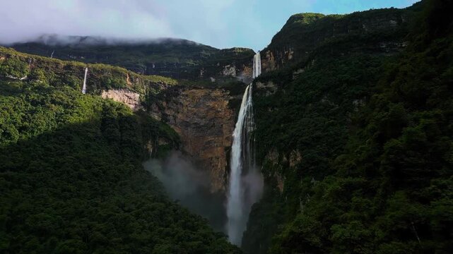 A breathtaking cinematic aerial drone sweep capturing the colossal two-tiered drop of Gocta Waterfall plunging down sheer jungle-clad cliffs in the remote Peruvian Andes.