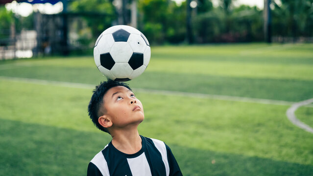 Kid boy leg kicking soccer ball on green grass field action. conceptual metaphor for youth sports training team competition fitness health wellness and active lifestyle