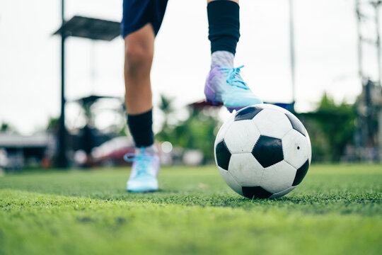 Kid boy leg kicking soccer ball on green grass field action. conceptual metaphor for youth sports training team competition fitness health wellness and active lifestyle