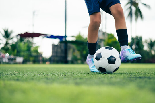 Kid boy leg kicking soccer ball on green grass field action. conceptual metaphor for youth sports training team competition fitness health wellness and active lifestyle