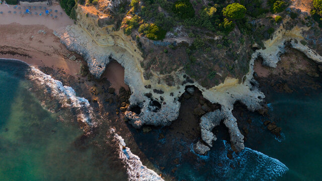 aerial view of rocky coastline with ocean waves and beach interaction in serene natural setting, brown and green tones, perspective from above, travel and landscape Praia dos Aveiros Portugal