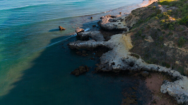 serene rock formations along a coastline with sandy beaches and ocean waves from an aerial view above the rocky outcrops and blue-green waters of a natural landscape.